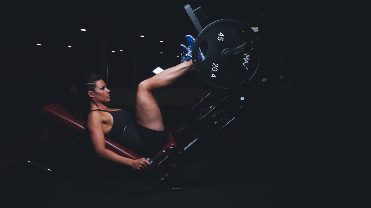 A woman engages in an intense leg press workout at the gym, showcasing strength and fitness.